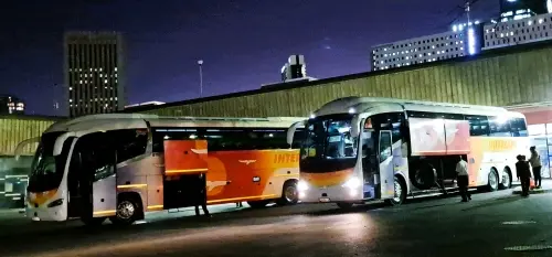Passengers boarding 2 Intercape buses at Cape Town Station in the evening