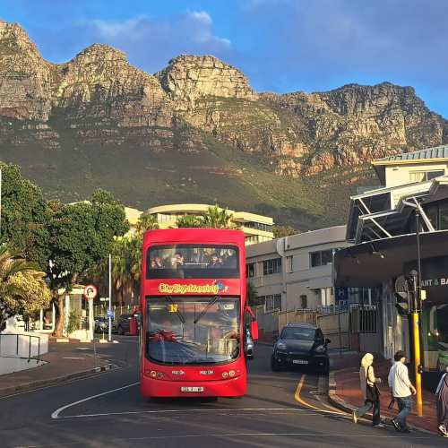 City Sightseeing bus in Camps Bay with the Twelve Apostles mountain range in the background