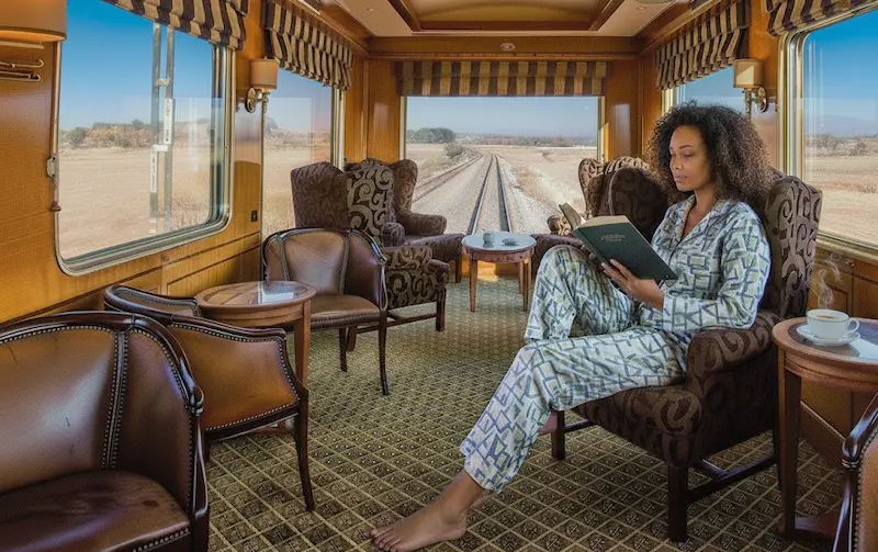 Lady reading a book in the observation car of The Blue Train